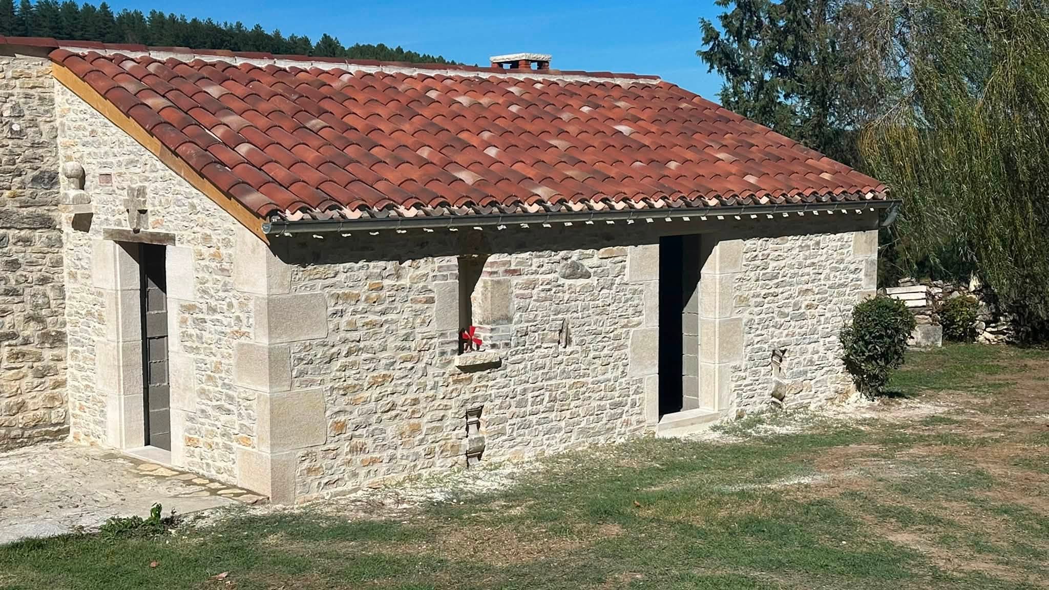 Façade en pierre claire sous une toiture de tuiles